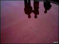 Moradores de Bagdá têm imagem refletida em poça de sangue no bairro de Cidade Sadr