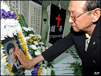 Một người đàn ông đứng trước di ảnh của con tin bị giết chết