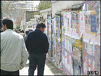 İranlılar seçim öncesi duvarlardaki afişlere bakıyor