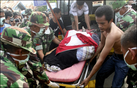 Workers and soldiers take the body of an earthquake victim out of an ambulance at a hospital in Padang, Sumatra