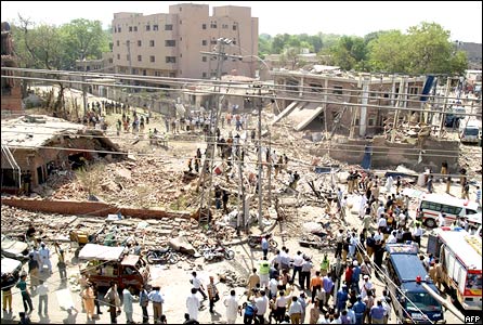 Pakistani security officials and volunteers gather in front of the destroyed police emergency response office building following a suicide car bomb attack in Lahore on May 27, 2009
