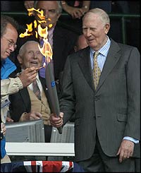 سر راجر بینسٹر اولمپک مشعل روشن کر رہے ہیں