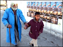 Seçim afişlerinin önünden geçen çocuk ve yaşlı bir adam