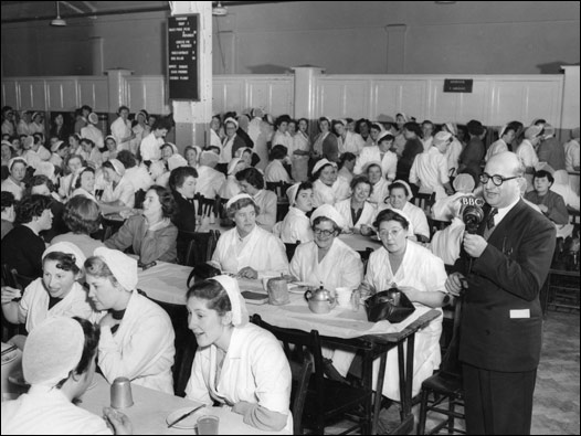 BBC Türkçe'den Mehmet Refiğ, öğle tatili sırasında bir çikolata fabrikasının yemekhanesinde. İki Şehir adlı adlık programın bu bölümünde Giresun ile Birmingham yakınlarındaki Bourneville kentleri ele alınıyor. İngiltere'deki bu çikolata üretim merkezi, o dönemde Giresun'da yetişen fındıkların dünyadaki en büyük müşterilerindendi. 07/01/1955 © BBC