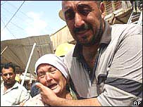 Funcionário da equipe de socorro ajuda idosa em Bagdá