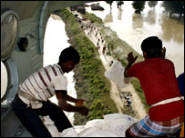 हेलीकॉप्टर से राहत सामग्री गिराते कर्मचारी