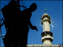 Menino palestino com uma arma de brinquedo em frente a uma mesquita, em Gaza