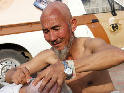 A man with a shaved head shaving another man's head