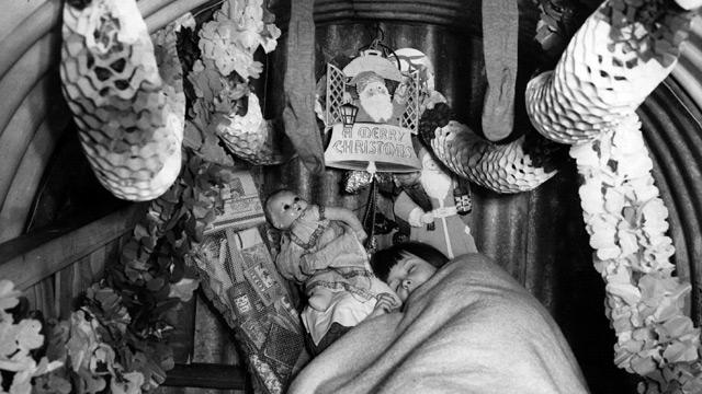 A child sleeps in an air-raid shelter festooned with Christmas decorations – a not uncommon sight in December 1940. 