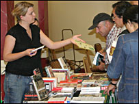  یک دختر اطلاعیه روی میز کتاب را به حضار می دهد