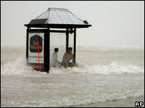 Homens esperam em ponto de ônibus coberto pelas águas do mar durante passagem do furacão Rita no sul da Flórida