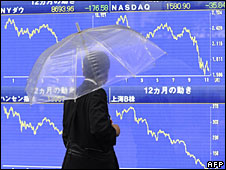 Một người đi đường dừng chân trước bảng giá chứng khoán điện tử ở Tokyo