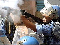 पुलिस आँसू गैस का गोला छोड़ते हुए