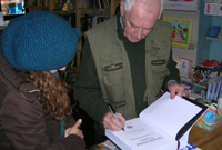 John Davies yn arwyddo un o'r copiau cyntaf o'r llyfr yn siop Caban, Caerdydd
