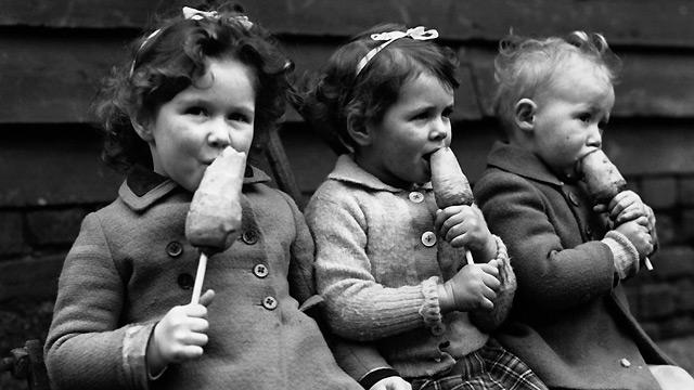 Three young children make do with carrots on sticks, a healthier alternative to ice cream which was unavailable during World War Two due to rationing.