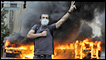 Smoke billows from a burning bus as a supporter of defeated Iranian presidential candidate Mir Hossein Mousavi flashes the victory sign during a protest in Tehran on June 13, 2009