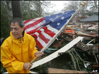 Garron Lenaz recupera uma bandeira americana entre os escombros da sua casa em Mississipi