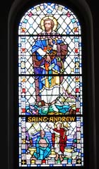 Stained glass window with Saint Andrew depicted barefoot in water, holding a fishing line, with a tiny fishing boat visible behind him. Saint Rule is depicted lower down bringing Andrew's remains to Fife