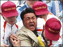 Manifestante é contido por policiais japoneses durante passagem da tocha olímpica em Nagano