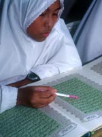A girl wearing a headscarf reads the Qur'an