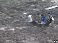 Homens caminham sobre a lama para ajudar no resgate