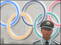 Một nhân viên an ninh đứng trước biểu tượng Olympics ở quảng trường Thiên An Môn