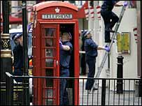 Policiais revistam cabine telefônica em Londres
