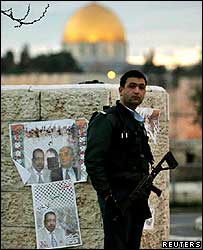 Policial israelense ao lado de cartaz de campanha palestino em Jerusalém