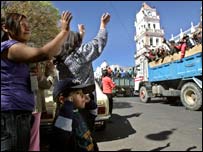 Pessoas acenam para mineiros num caminhão