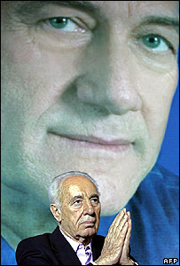 Ehud Almert em um encontro do partido com a foto de Ehud Olmert ao fundo