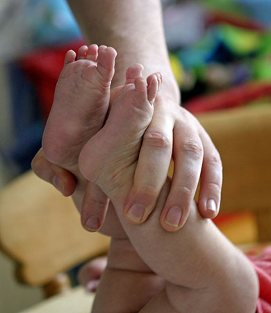 Baby's legs being held, photo by Tom Ang