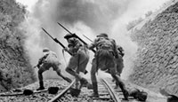 Bayonet-fixed rifles held firmly, members of the British 8th Army are pictured heading into the smoke of battle as they rush a Sicilian railway strongpoint