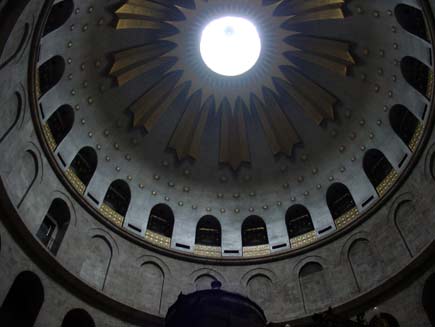 Inside of the Church of the Holy Sepulchre dome.  Light streams in from the opening at the top, illuminating the gold sunburst and star patterns on the ceiling