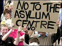 Manifestantes seguram cartaz em protesto contra isolamento em centros de abrigo para refugiados