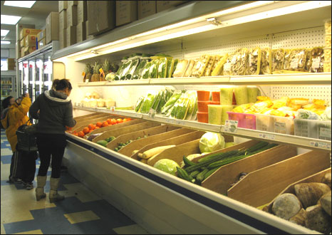 Một phụ nữ và trẻ con tại quầy rau qủa ở siêu thị Đại Nam