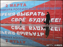 Mulher passa em frente a propaganda eleitoral em São Petersburgo