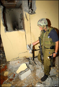 Soldado israelense observa prédio danificado por mísseis no assentamento de Nissanit