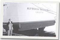 Y Capten Michael Edwin Hughs gydag un o'r llongau trugaredd sy'n rhoi gobaith i'r tlawd a'r anghennus.