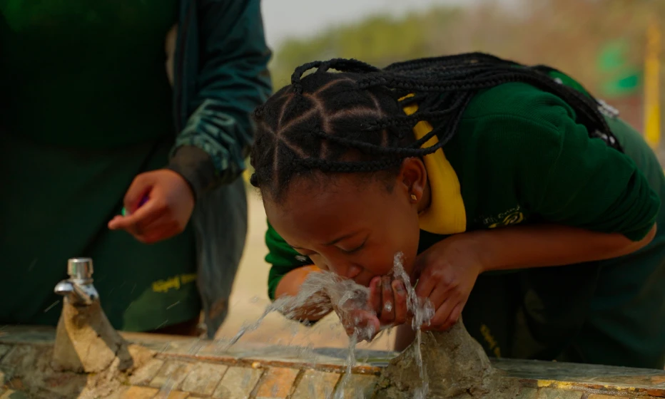 Young girl drinking from a water fountain.