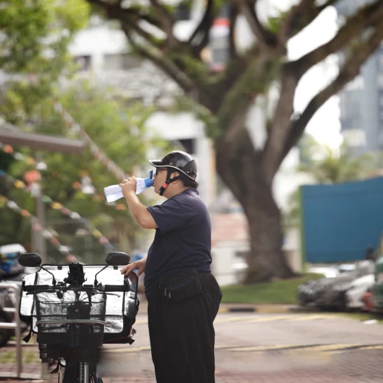 A cyclist drinking water stood next to his bike.