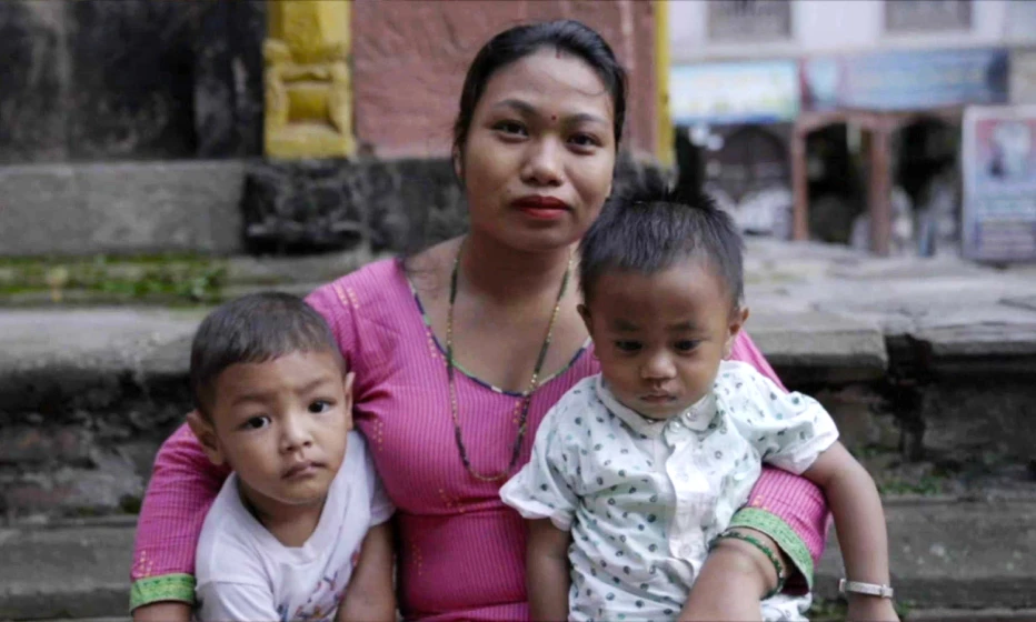 A mother with her arms wrapped around two young children.