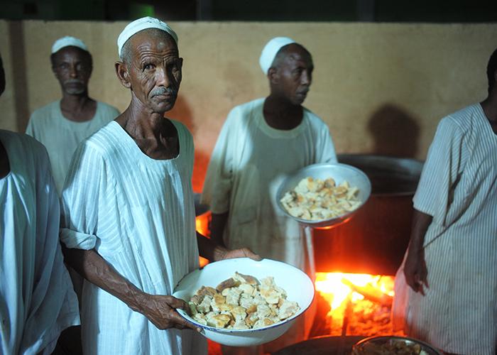 Sudanese men dish out bowls of bread at an Islamic feast in Kadabas on the edge of the Sahara.