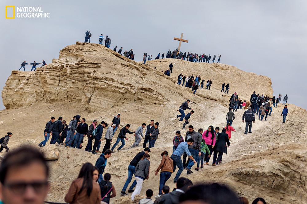 Arab Christians pray beneath a cross during the Feast of Epiphany near the banks of the Jordan River. Image from the December 2014 issue of National Geographic magazine. Photo © John Stanmeyer/National Geographic